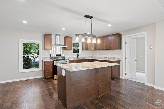 kitchen featuring a wealth of natural light, wall chimney exhaust hood, pendant lighting, stainless steel stove, and dark hardwood / wood-style floors