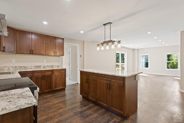 kitchen featuring light stone countertops, dark hardwood / wood-style flooring, stainless steel range with electric cooktop, decorative light fixtures, and a kitchen island