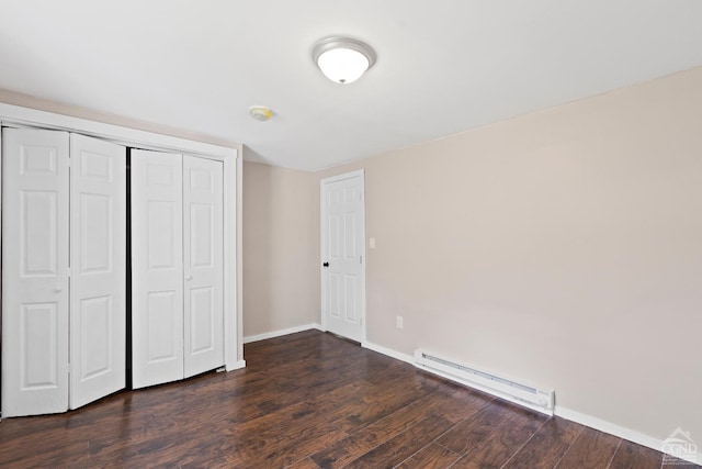 unfurnished bedroom with a closet, dark hardwood / wood-style floors, and a baseboard heating unit