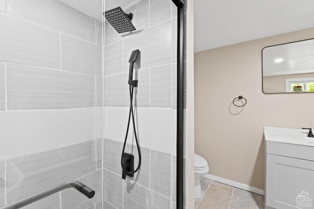 bathroom featuring tile patterned flooring, a tile shower, vanity, and toilet