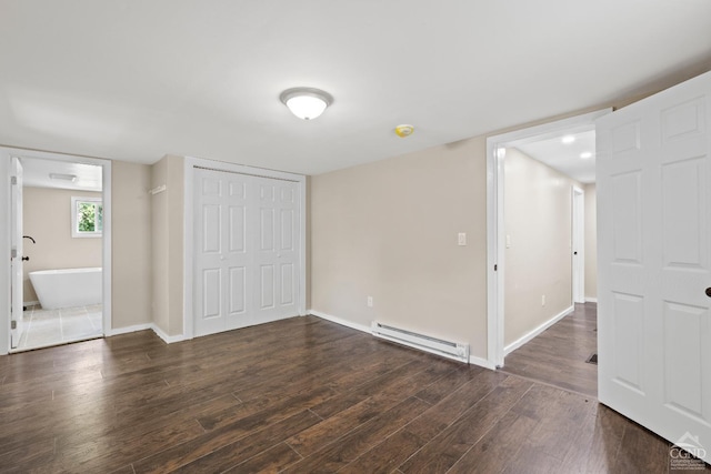 unfurnished bedroom with a closet, dark hardwood / wood-style flooring, connected bathroom, and a baseboard heating unit