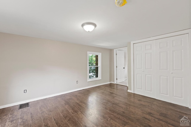 unfurnished bedroom with dark hardwood / wood-style flooring and a closet