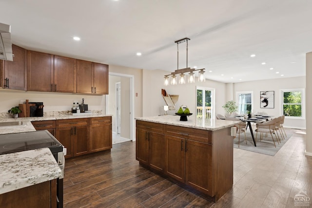 kitchen featuring light stone countertops, dark hardwood / wood-style flooring, pendant lighting, electric range, and a kitchen island