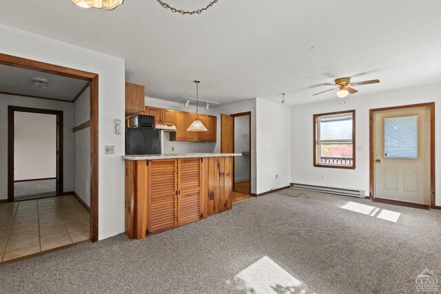 kitchen featuring kitchen peninsula, pendant lighting, light colored carpet, and a baseboard heating unit