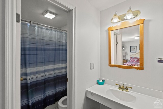 bathroom featuring toilet, curtained shower, and sink