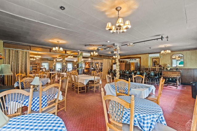 carpeted dining area with wood walls and a chandelier