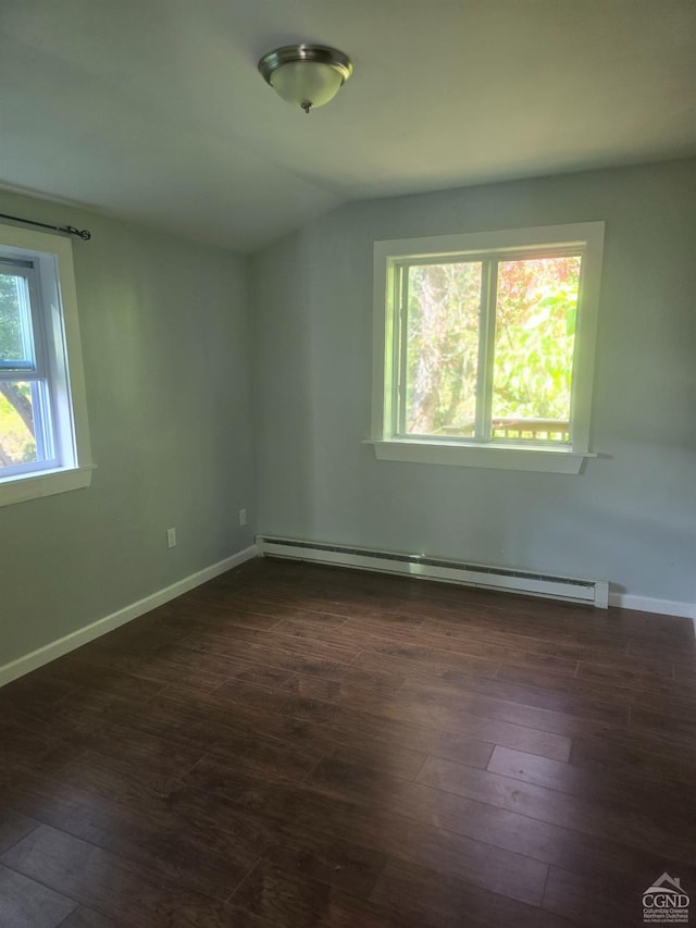 unfurnished room with vaulted ceiling, dark hardwood / wood-style floors, and a baseboard heating unit