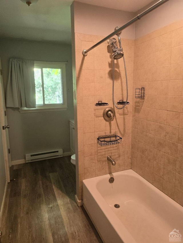 bathroom featuring toilet, wood-type flooring, baseboard heating, and tiled shower / bath