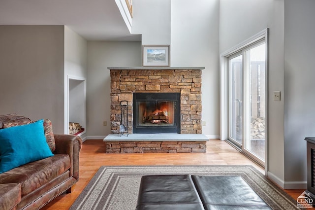 living room featuring a stone fireplace, plenty of natural light, and wood-type flooring