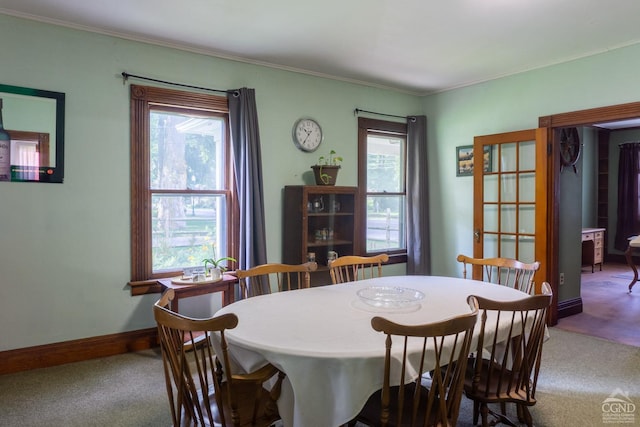 carpeted dining area featuring plenty of natural light and ornamental molding