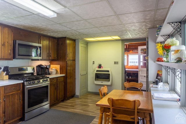 kitchen with dark brown cabinets, light wood-type flooring, appliances with stainless steel finishes, and heating unit