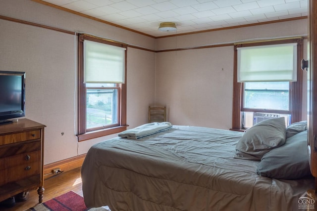 bedroom featuring cooling unit, wood-type flooring, and crown molding