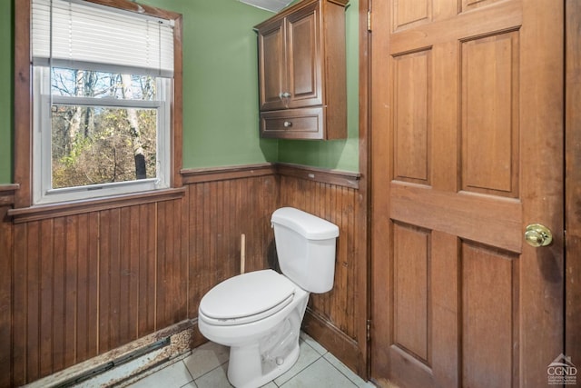 bathroom featuring tile patterned flooring, wood walls, and toilet