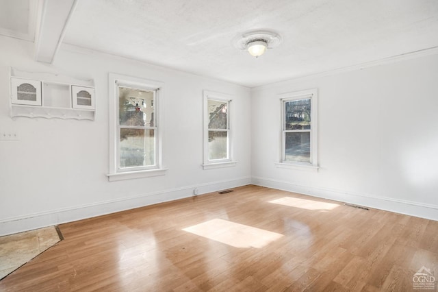 spare room with beamed ceiling, light hardwood / wood-style floors, and ornamental molding