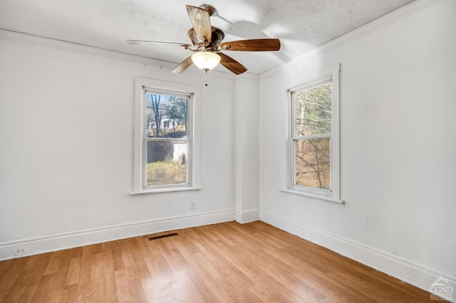 spare room featuring a wealth of natural light, light hardwood / wood-style flooring, and ornamental molding