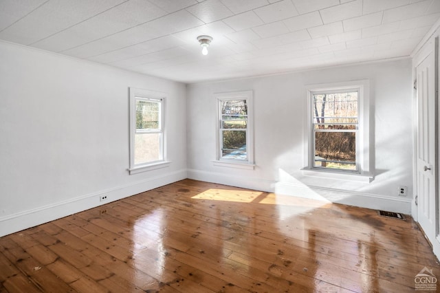 unfurnished room with hardwood / wood-style floors, a wealth of natural light, and crown molding