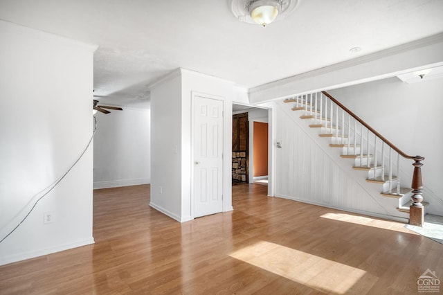 interior space with ceiling fan, wood-type flooring, and ornamental molding