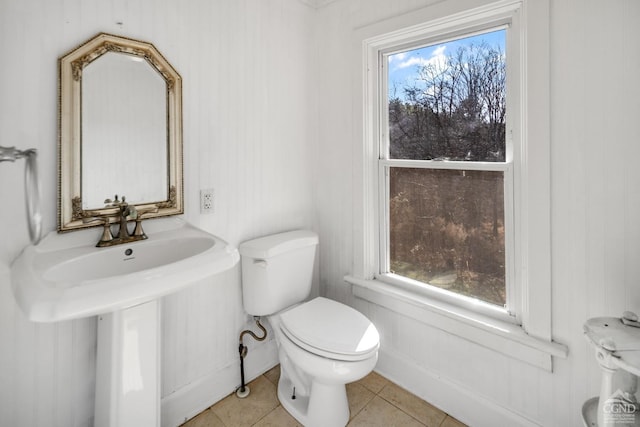 bathroom with toilet, plenty of natural light, and tile patterned flooring