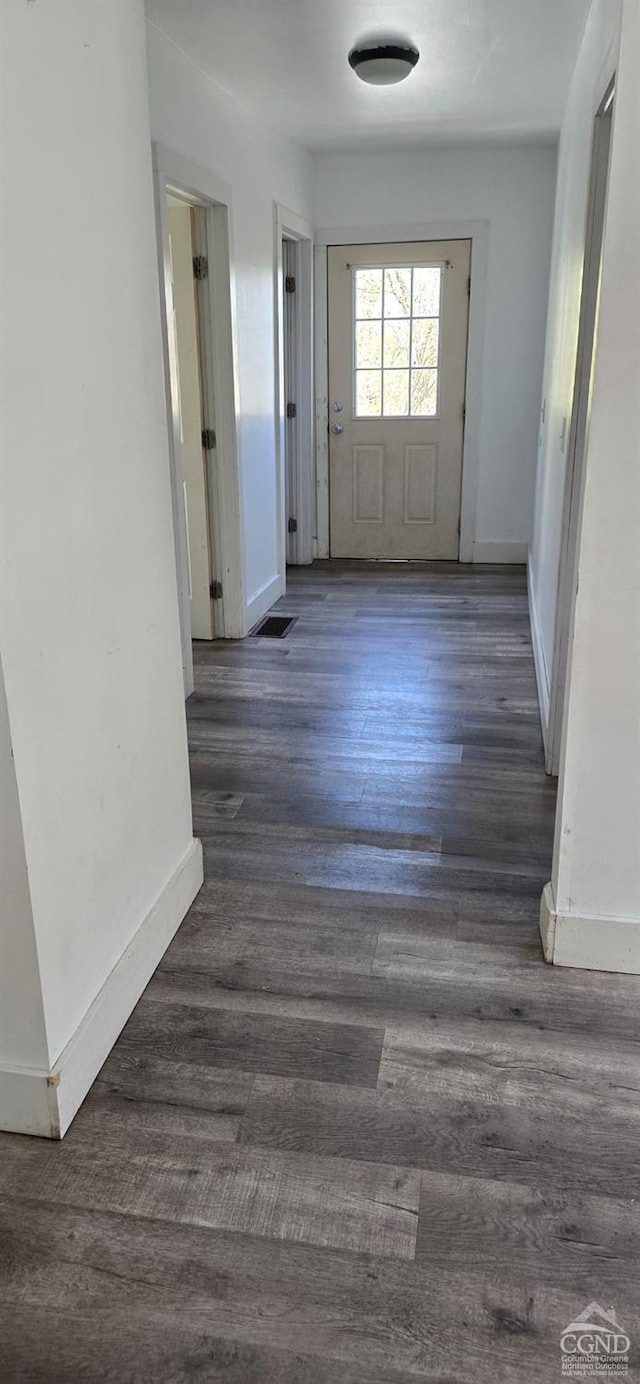 corridor featuring wood finished floors, visible vents, and baseboards