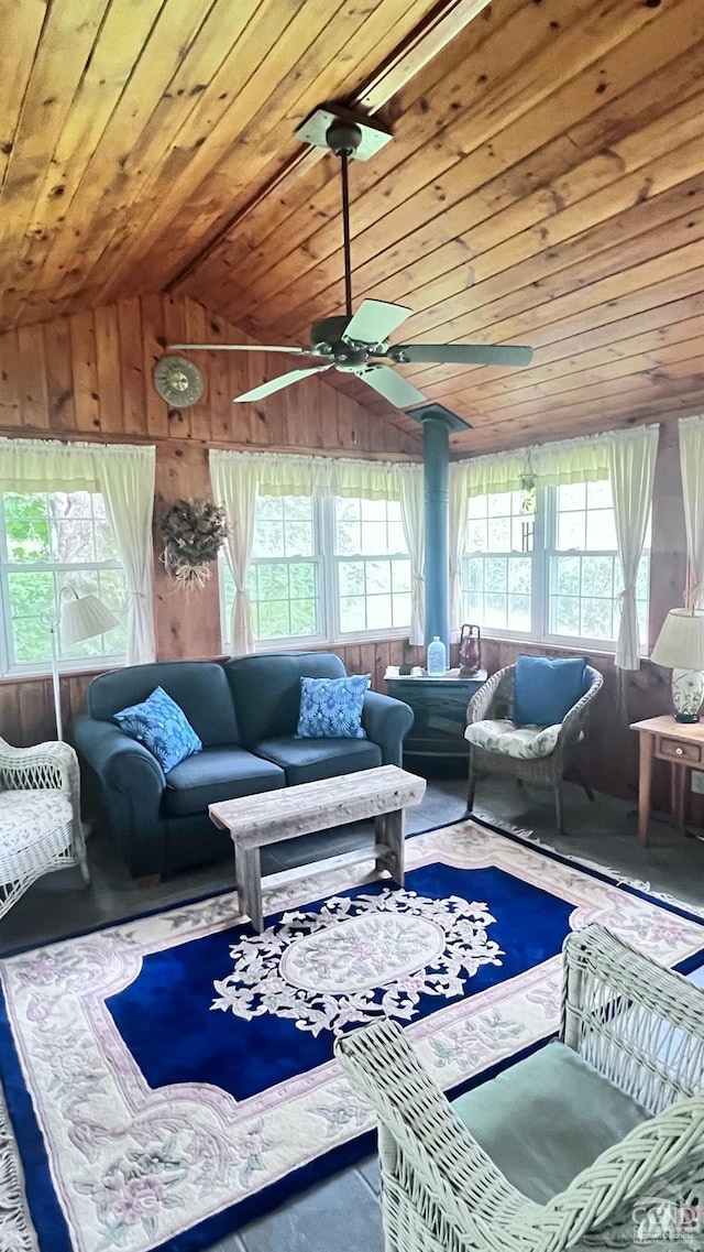 living room featuring a wood stove, ceiling fan, wood walls, vaulted ceiling, and wood ceiling