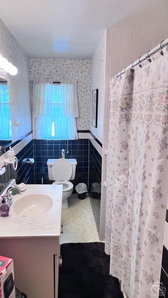 bathroom with a wealth of natural light, toilet, and tile walls