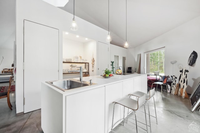 kitchen with vaulted ceiling, concrete flooring, a kitchen island with sink, and a sink