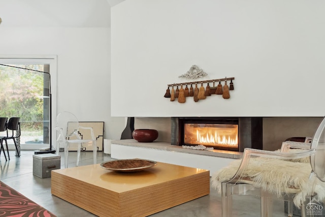 sitting room with a glass covered fireplace, finished concrete floors, and plenty of natural light