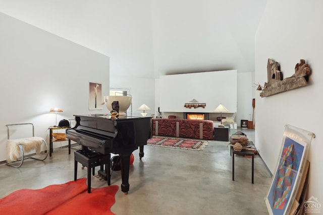 living area with a fireplace, a high ceiling, and finished concrete floors
