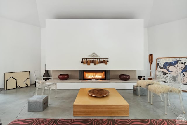 living room featuring concrete flooring and a warm lit fireplace