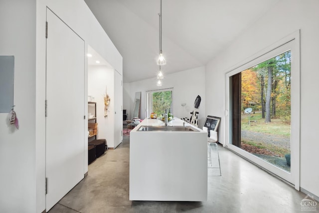 kitchen featuring a kitchen island with sink, concrete floors, white cabinetry, vaulted ceiling, and pendant lighting