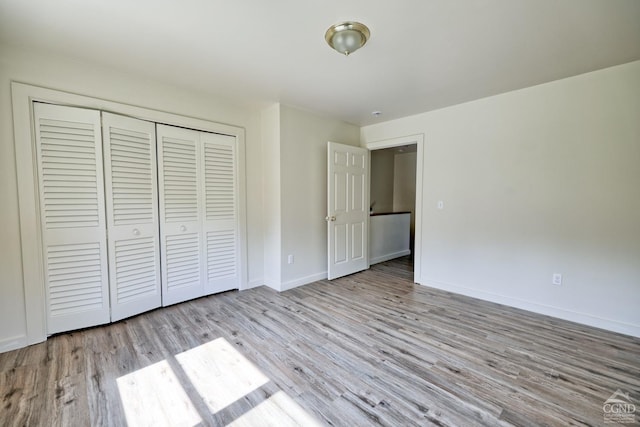 unfurnished bedroom with a closet and light hardwood / wood-style floors