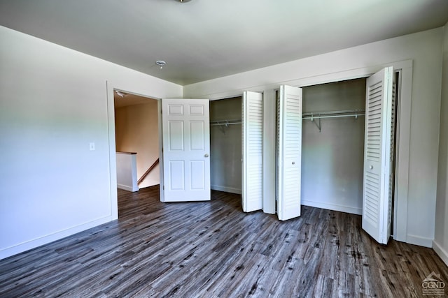 unfurnished bedroom with dark wood-type flooring and multiple closets