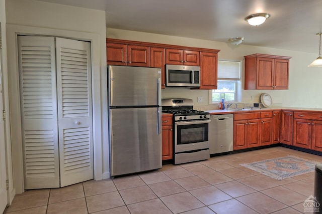 kitchen with light tile patterned floors, hanging light fixtures, and appliances with stainless steel finishes