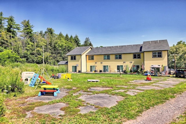 back of house with a playground and a yard