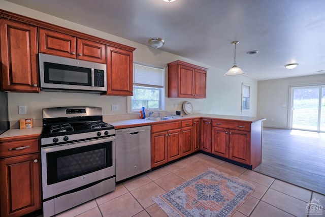 kitchen featuring light tile patterned flooring, kitchen peninsula, stainless steel appliances, and hanging light fixtures