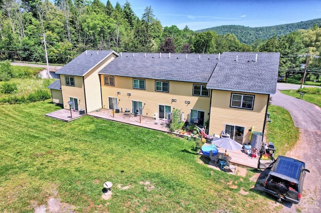 back of property featuring a deck and a lawn