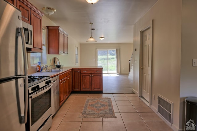 kitchen with sink, kitchen peninsula, pendant lighting, light tile patterned flooring, and appliances with stainless steel finishes