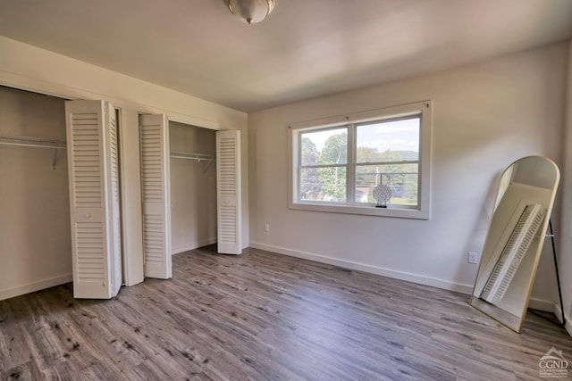 unfurnished bedroom with two closets and light hardwood / wood-style floors