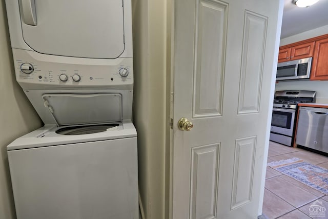 laundry room featuring stacked washer / drying machine and light tile patterned flooring