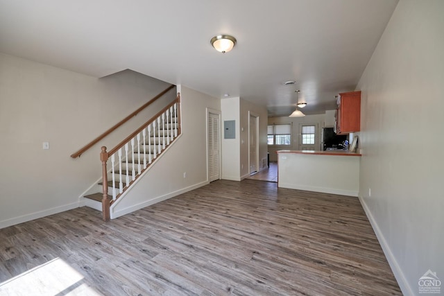 unfurnished living room with electric panel and light wood-type flooring