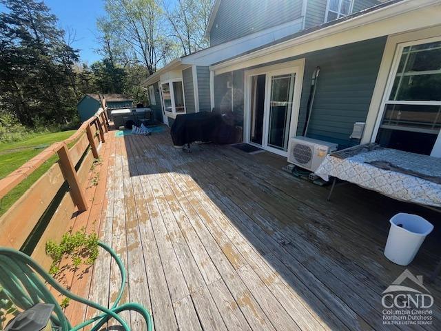 deck featuring a grill, a jacuzzi, and ac unit