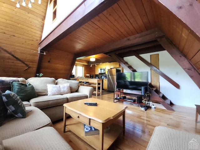 living room featuring beamed ceiling, wood walls, and light hardwood / wood-style flooring