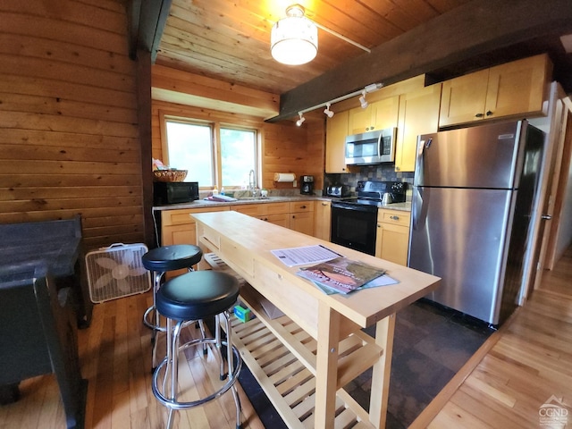 kitchen featuring light brown cabinets, sink, dark hardwood / wood-style flooring, wood walls, and black appliances