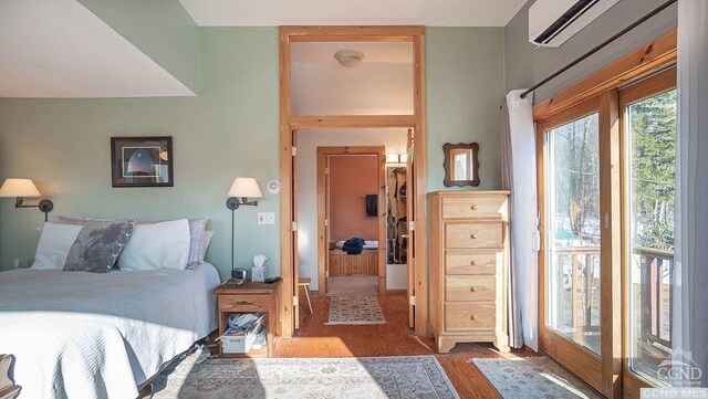 bedroom featuring access to outside, hardwood / wood-style flooring, and a wall mounted AC