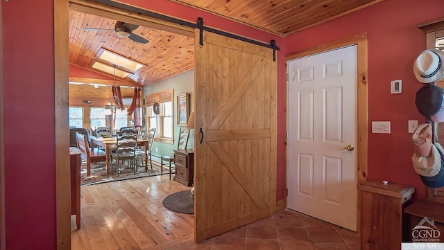 hall featuring a barn door, lofted ceiling with skylight, hardwood / wood-style floors, and wood ceiling