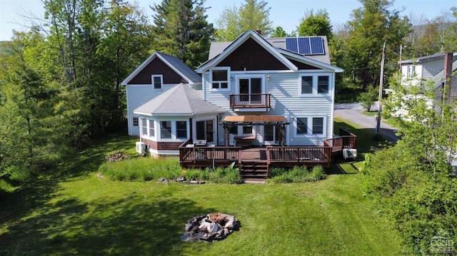 back of property featuring a wooden deck, a yard, and a fire pit