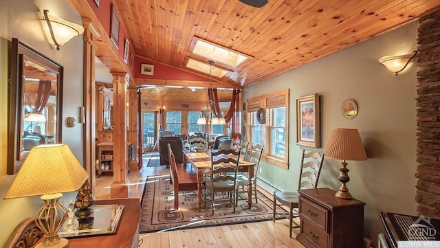 dining space featuring vaulted ceiling with skylight, ornate columns, light wood-type flooring, and wooden ceiling