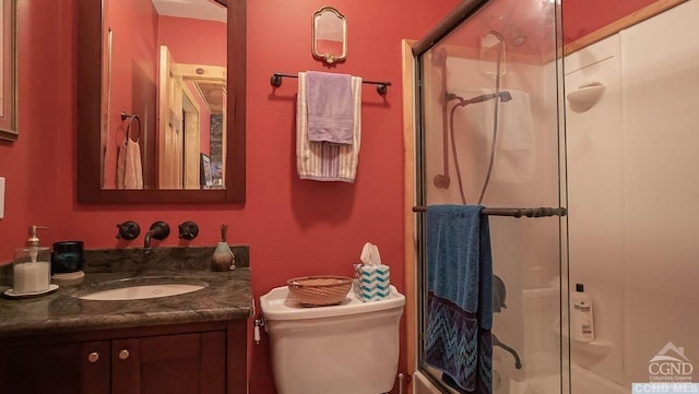 bathroom featuring vanity, a shower with shower door, and toilet