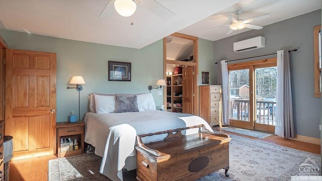 bedroom with ceiling fan, light wood-type flooring, access to outside, and a wall unit AC