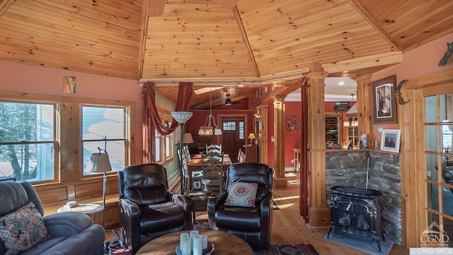 living room with decorative columns, vaulted ceiling, wood-type flooring, wooden ceiling, and a wood stove